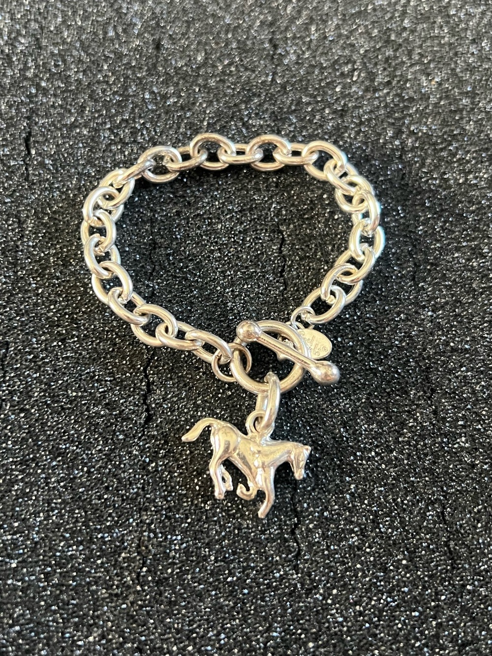 Silver tone link bracelet with a toggle clasp and a dangling horse charm